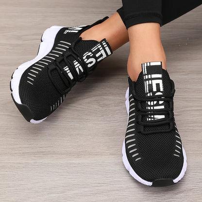 Black and white sneakers with brand logo on a wooden floor