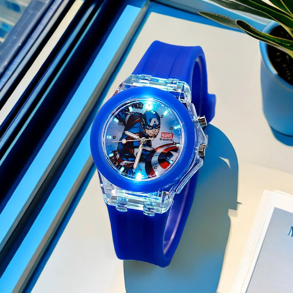 Blue superhero-themed watch on a reflective surface with a plant in the background