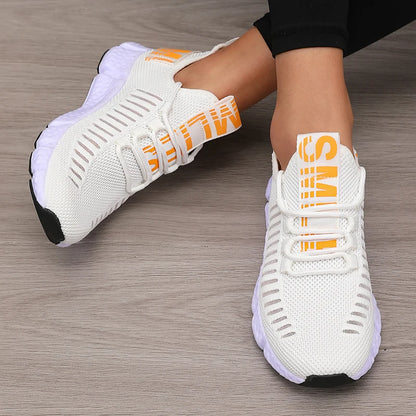 White sneakers with orange accents on a wooden floor