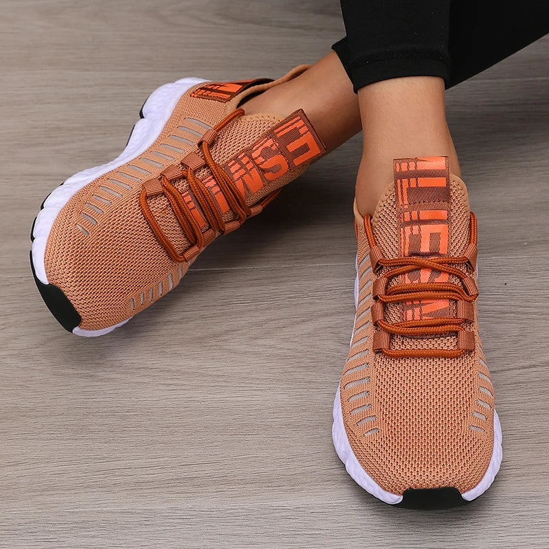 Orange sneakers with black soles on a wooden floor