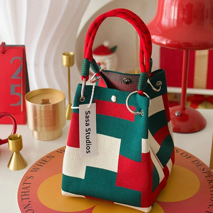 Colorful handbag with geometric pattern and 'Sasa Studios' tag on a decorative surface.