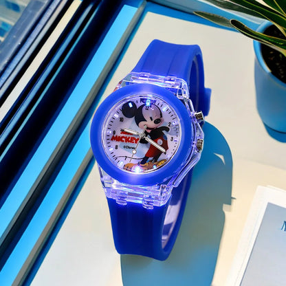Blue Mickey Mouse watch on a reflective surface with a plant in the background