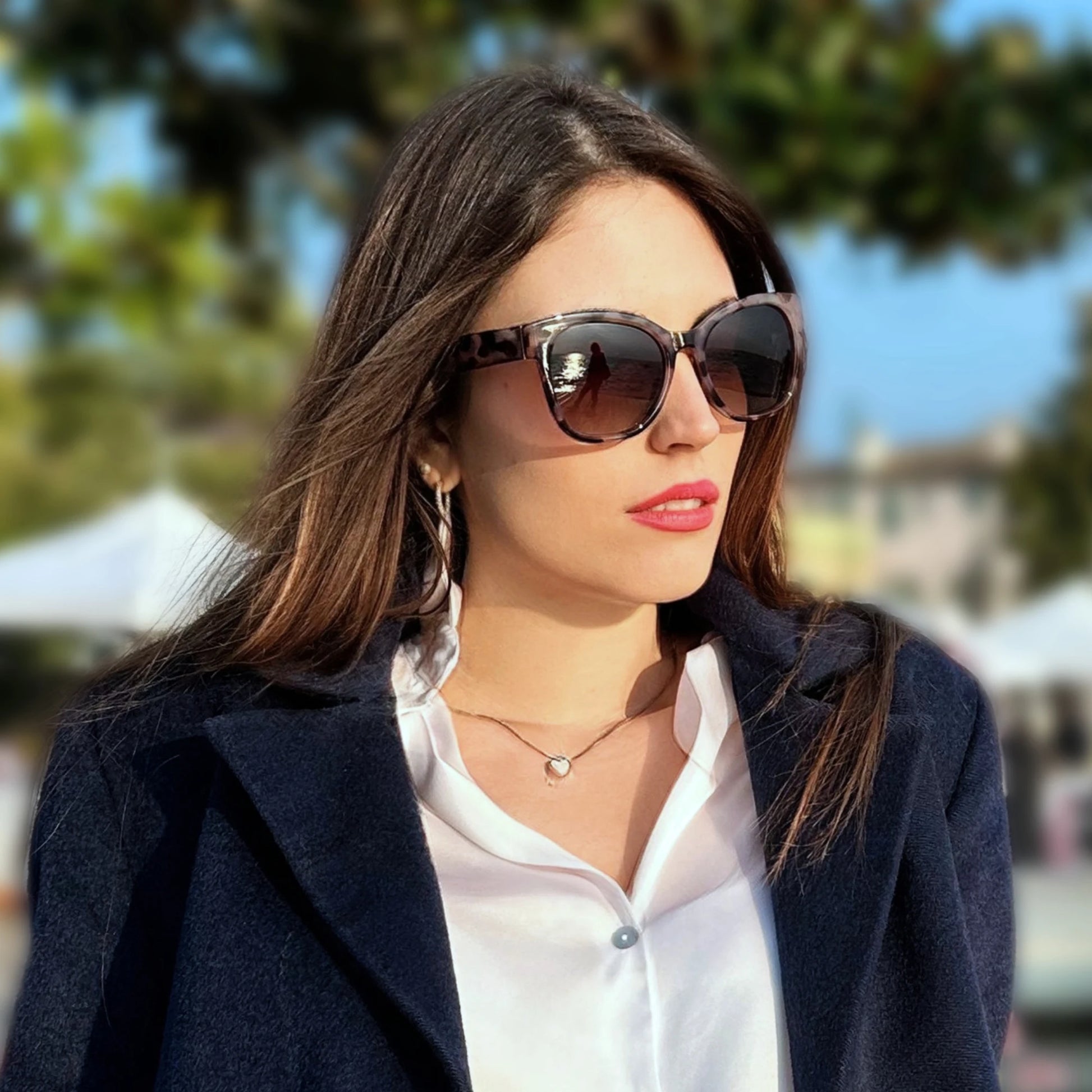 Woman wearing sunglasses and a dark coat outdoors