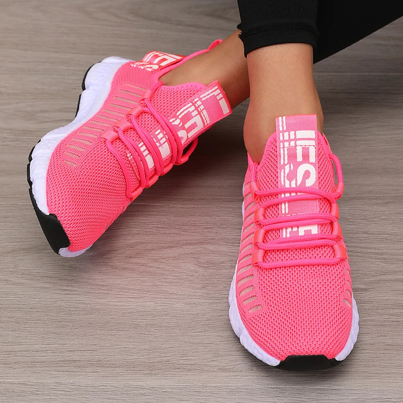 Pink athletic shoes with white soles on a wooden floor