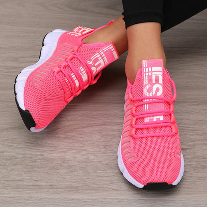 Pink athletic shoes with white soles on a wooden floor