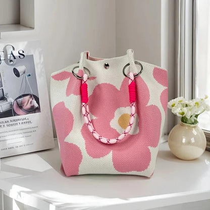 Pink floral-patterned bag with pink handles on a white surface.