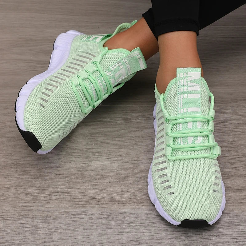 Light green running shoes with white soles on a wooden floor