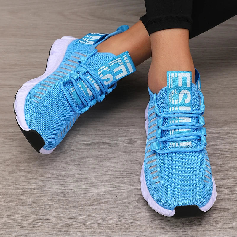 Blue athletic shoes with white soles on a wooden floor