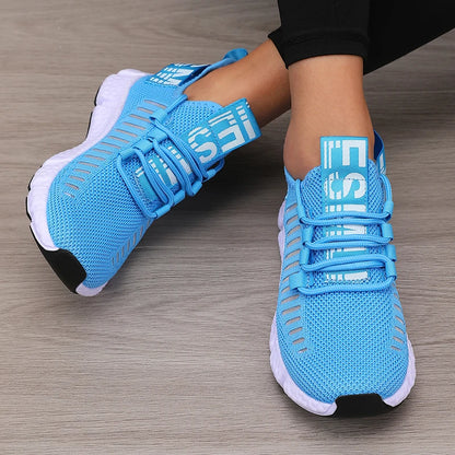 Blue athletic shoes with white soles on a wooden floor